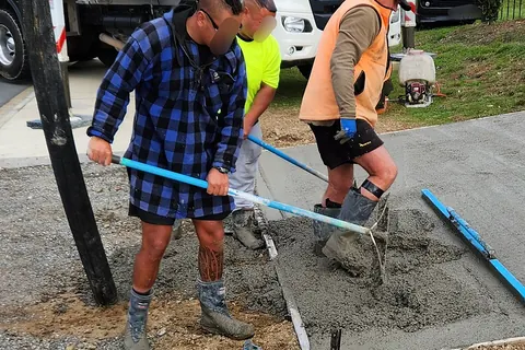 Workers spreading concrete for a driveway