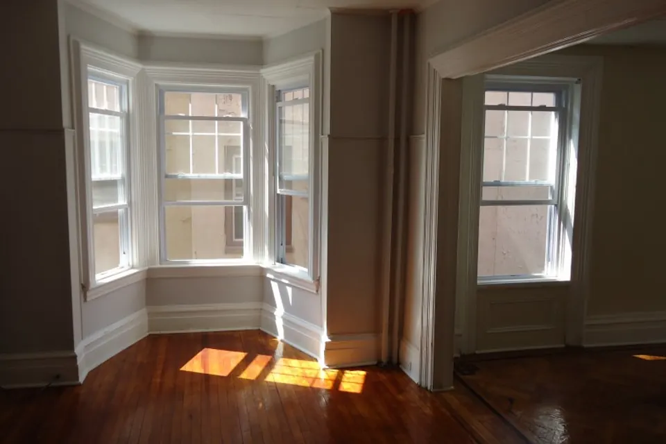 Sunlight falling across a home's hardwood floor and bay windows