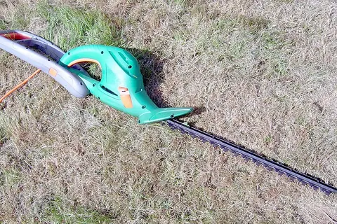 Electric hedge trimmer on grass