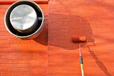 Paint roller beside a freshly painted wall