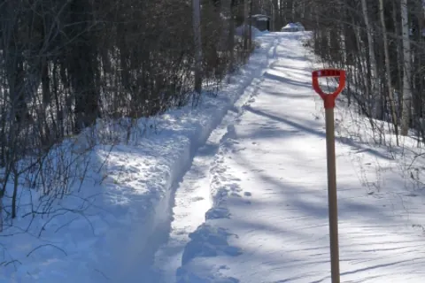 Snow shovel on a cleared snowy path